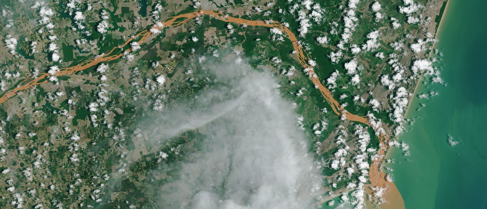 Imagem de satélite da foz do Rio Doce, com o rio tomado pela cor laranja dos rejeitos e manchando de marrom o Atlântico onde encontra o mar.